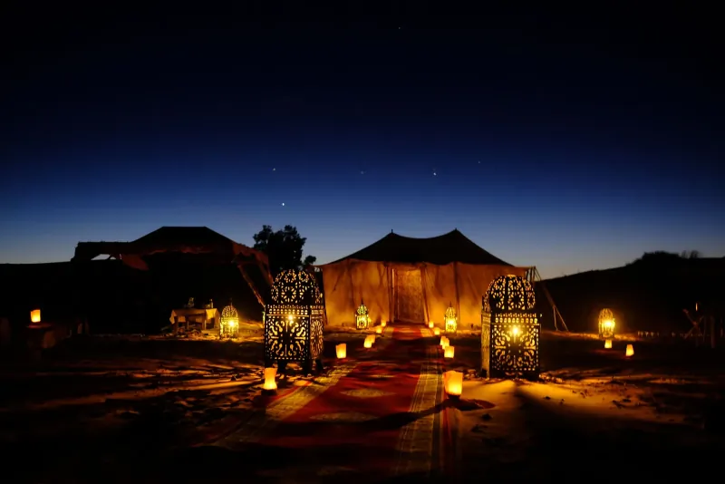 Desert camp illuminated beneath the night sky in Merzouga